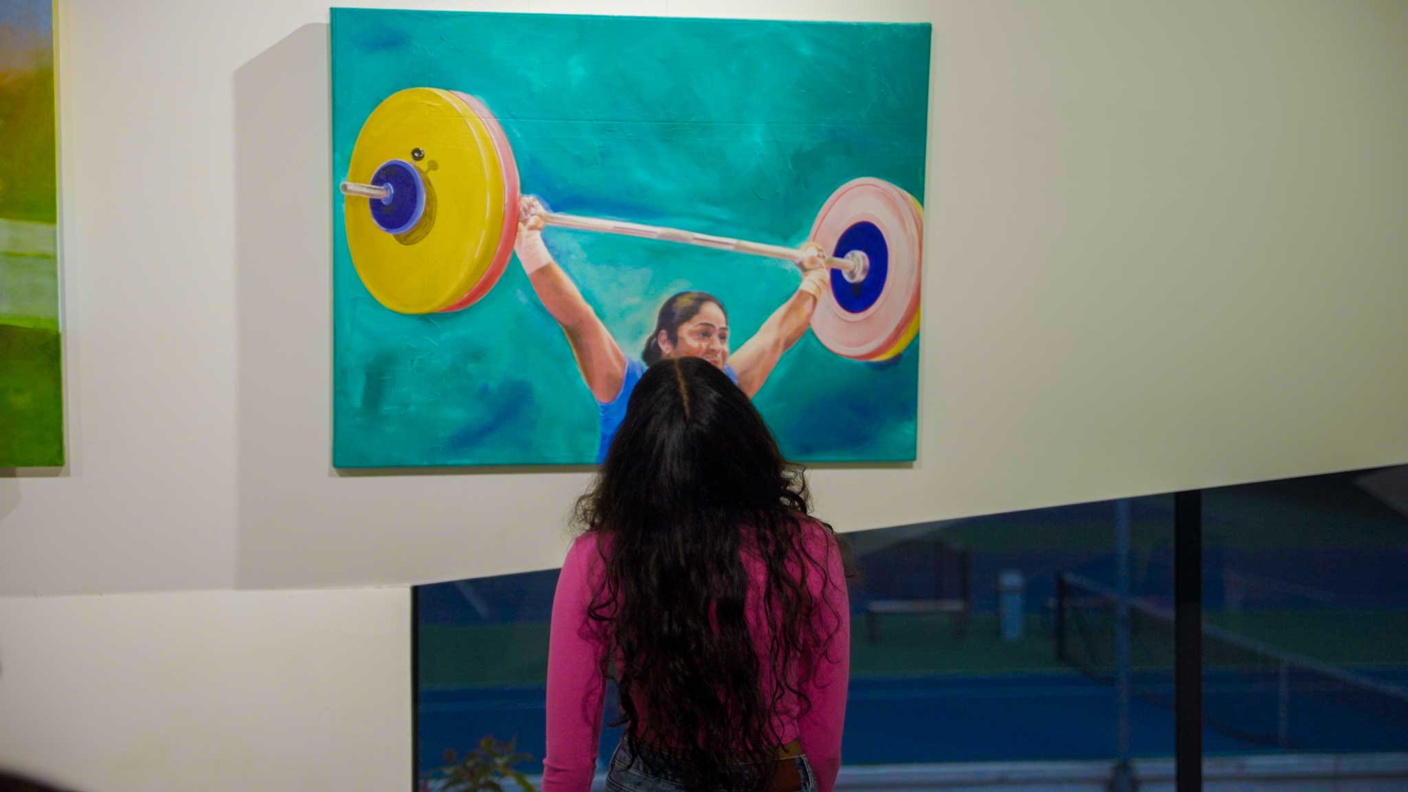 Woman viewing sports-themed artwork during Bengaluru’s Best Playcation cultural experience.